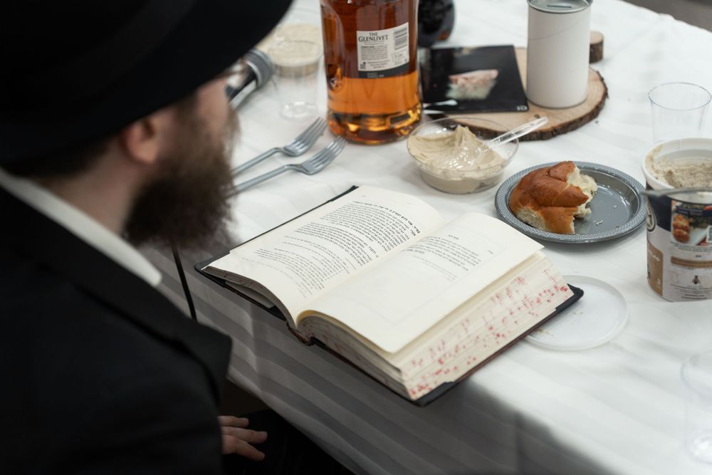 Religious text open on table with traditional foods and drinks.
