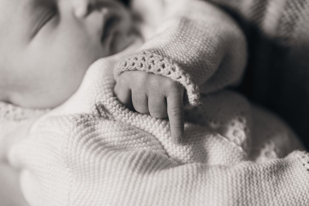 Close up of tiny baby hand grasping knitted fabric in black and white.