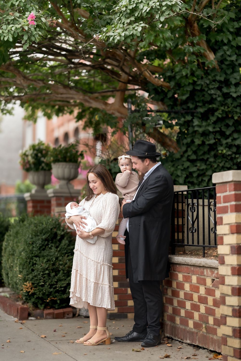 Family standing outdoors near decorative brick wall during a religious ceremony.