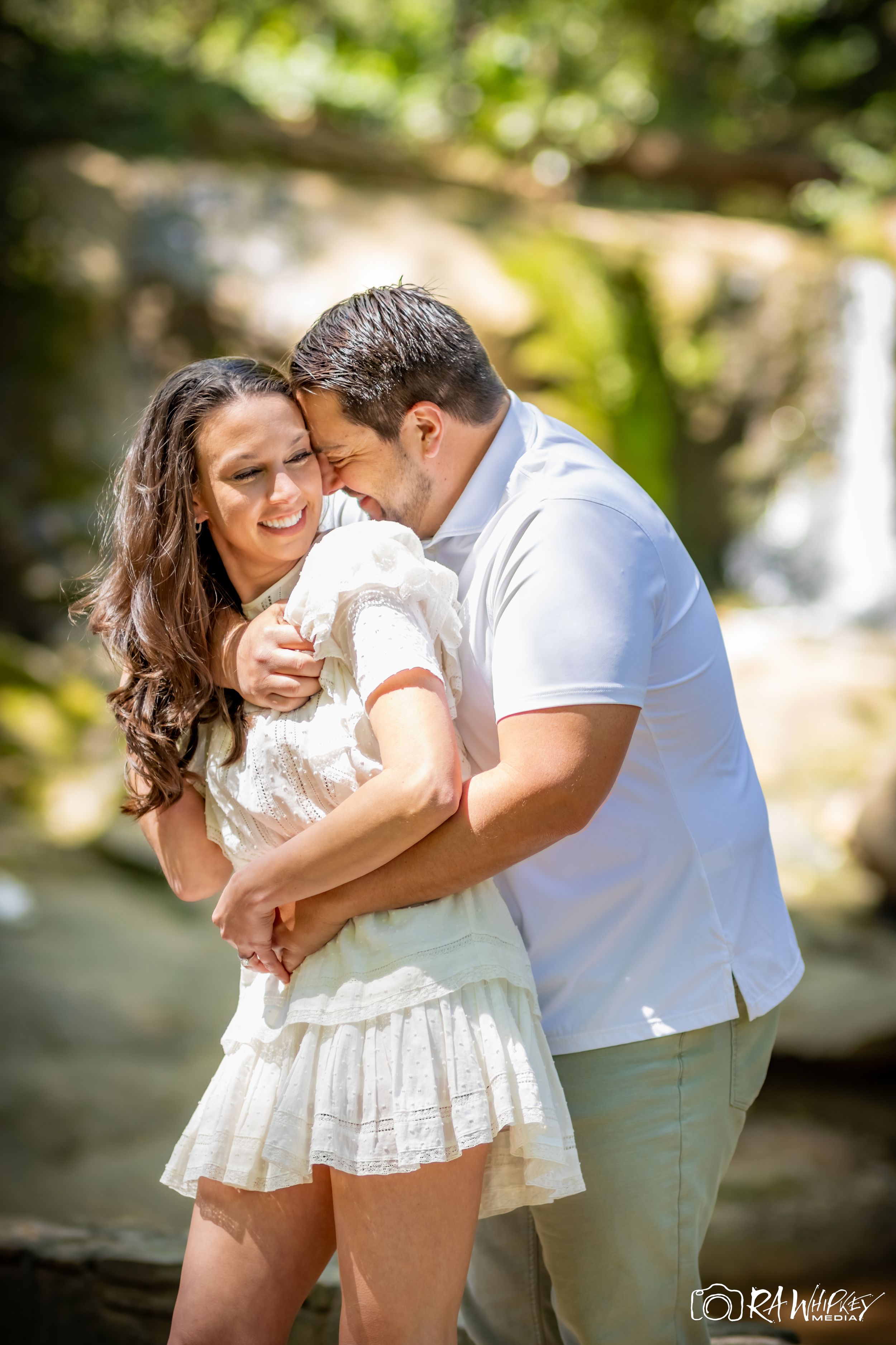 An intimate moment captured between a couple laughing together near a waterfall.