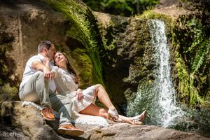 Couple relaxing together by a scenic waterfall on rocky terrain.