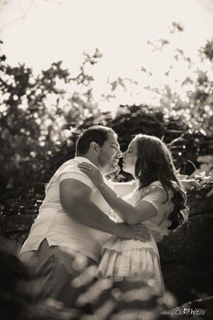 Black and white portrait of a couple sharing a tender moment outdoors.