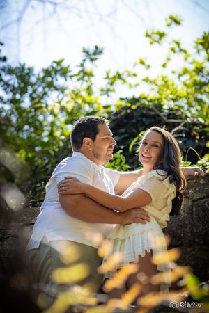 Happy couple embracing and laughing together in a sunny garden setting.