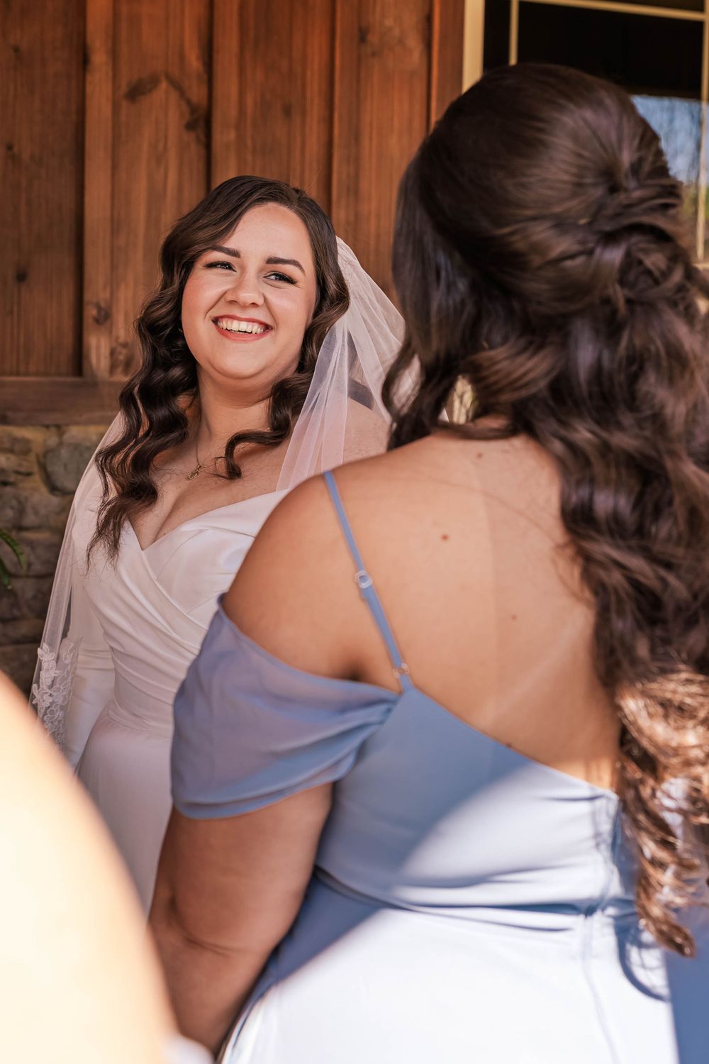 Wedding party members in light blue dresses and white gowns sharing joyful moments.