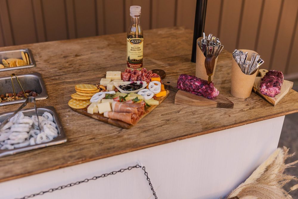 Rustic wooden table with various snacks and refreshments for wedding guests.