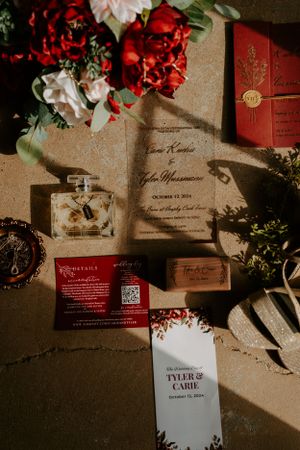 Wedding invitation suite in red and white with floral accents and dramatic lighting.