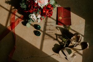 Wedding stationery details with red flowers and dramatic shadows.