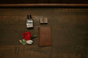 Wedding rings and details arranged on rustic wooden surface in warm lighting.
