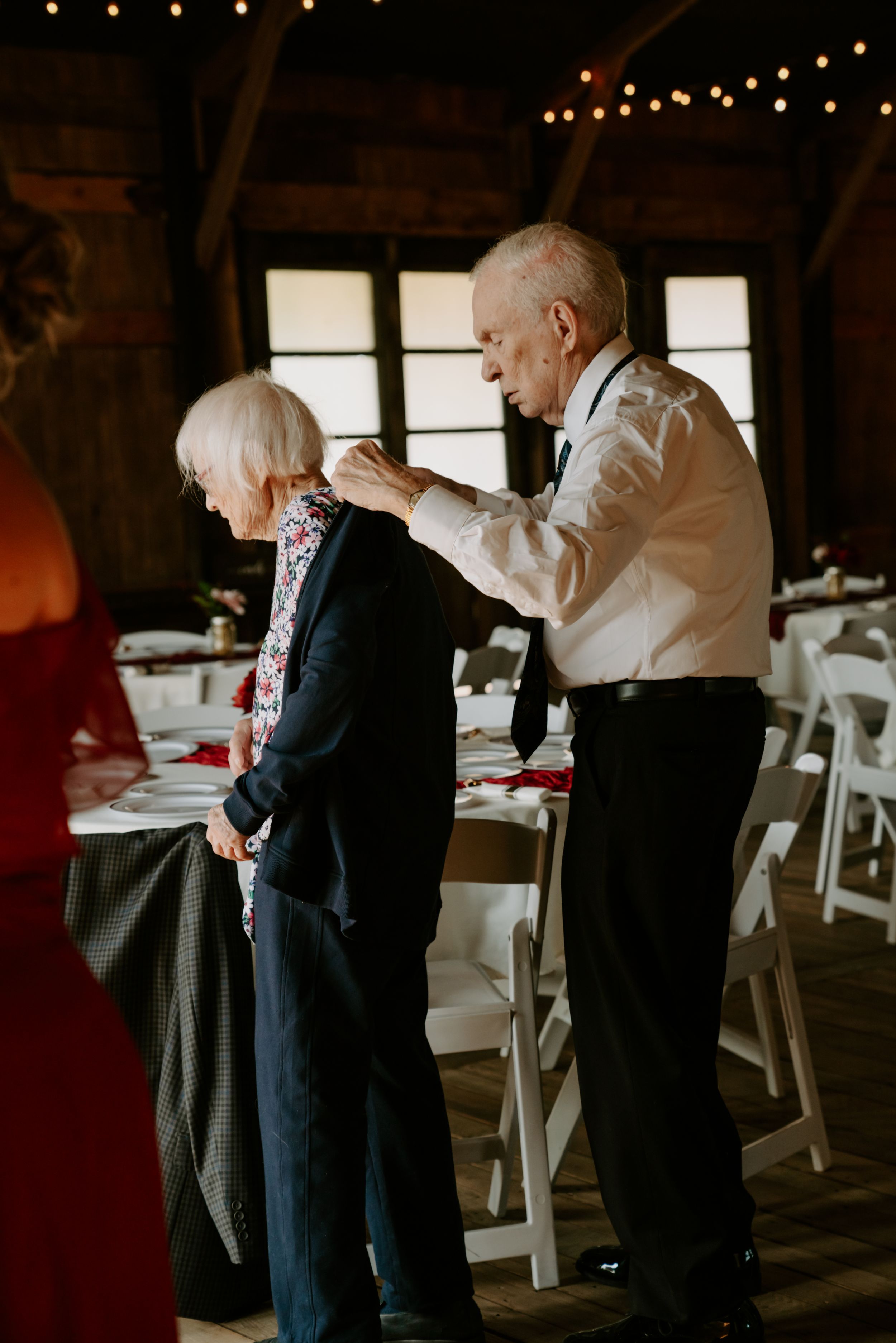 String lights illuminate a rustic barn interior set up for a wedding reception.