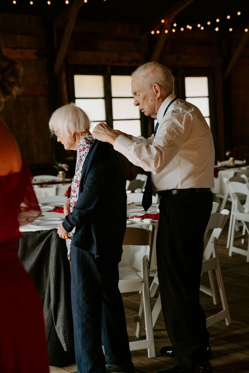 String lights illuminate a rustic barn interior set up for a wedding reception.
