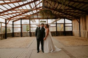 Panoramic view of empty rustic barn interior with wooden beams and natural lighting.