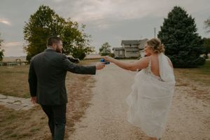 Couple holding hands while walking through outdoor venue on their wedding day.