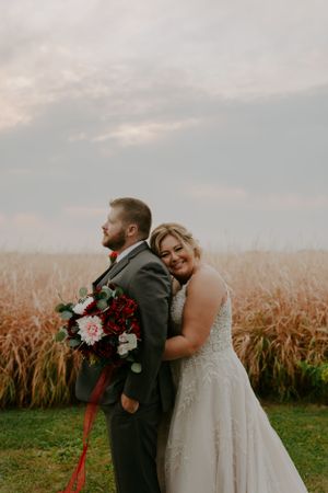 Romantic moment between newlyweds against backdrop of autumn cornfield.
