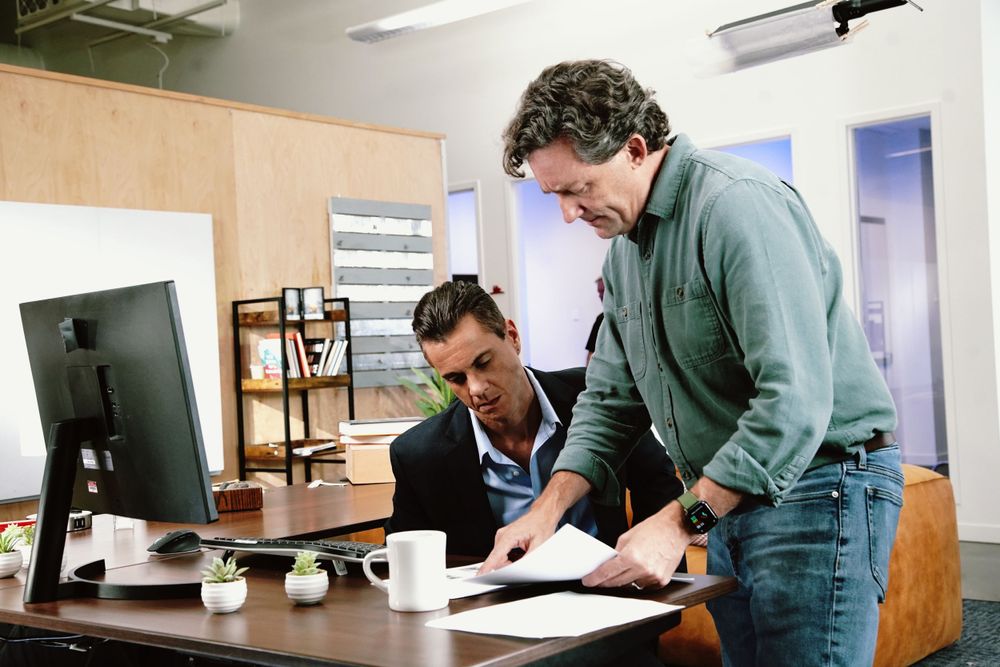 Film crew reviewing materials and working together at a desk in an office environment.
