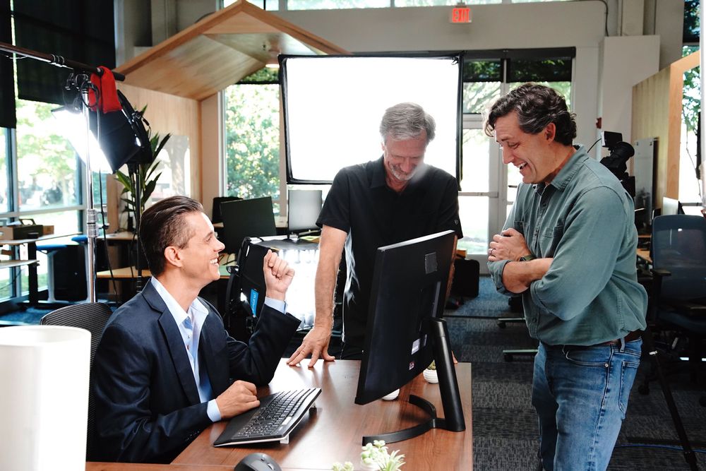 Film crew members collaborating and reviewing footage in an indoor workspace.
