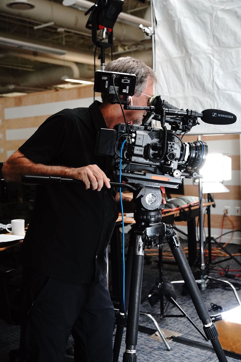 Professional videographer operating a mounted camera rig in a studio setting.
