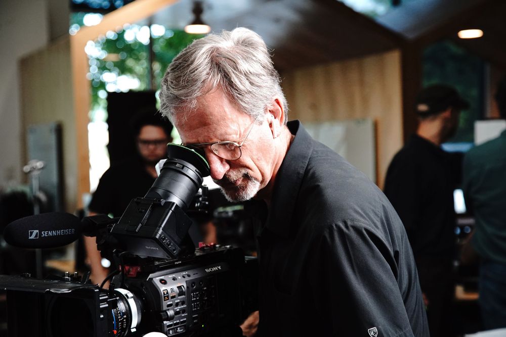 Camera operator working with professional video equipment in low light conditions.