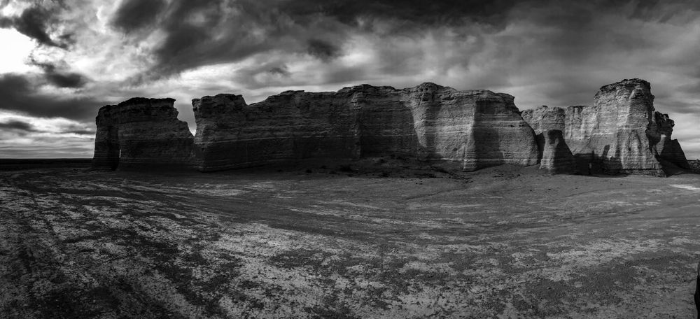 Panoramic view of massive limestone cliffs and rock formations under a dramatic stormy sky.