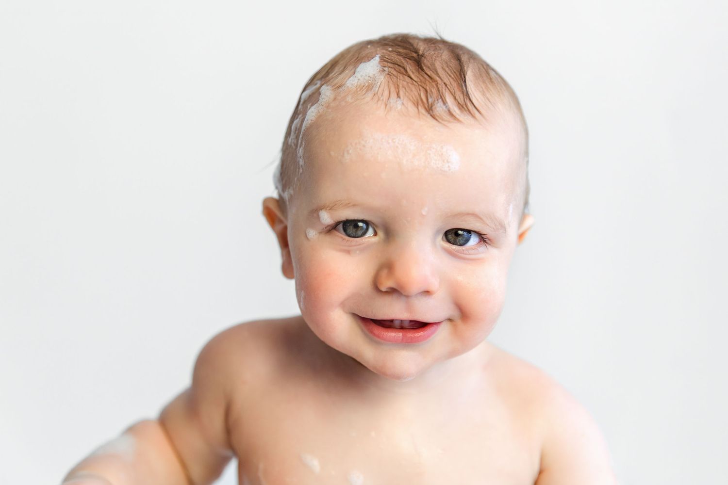 Baby after bubble bath with soap suds on face