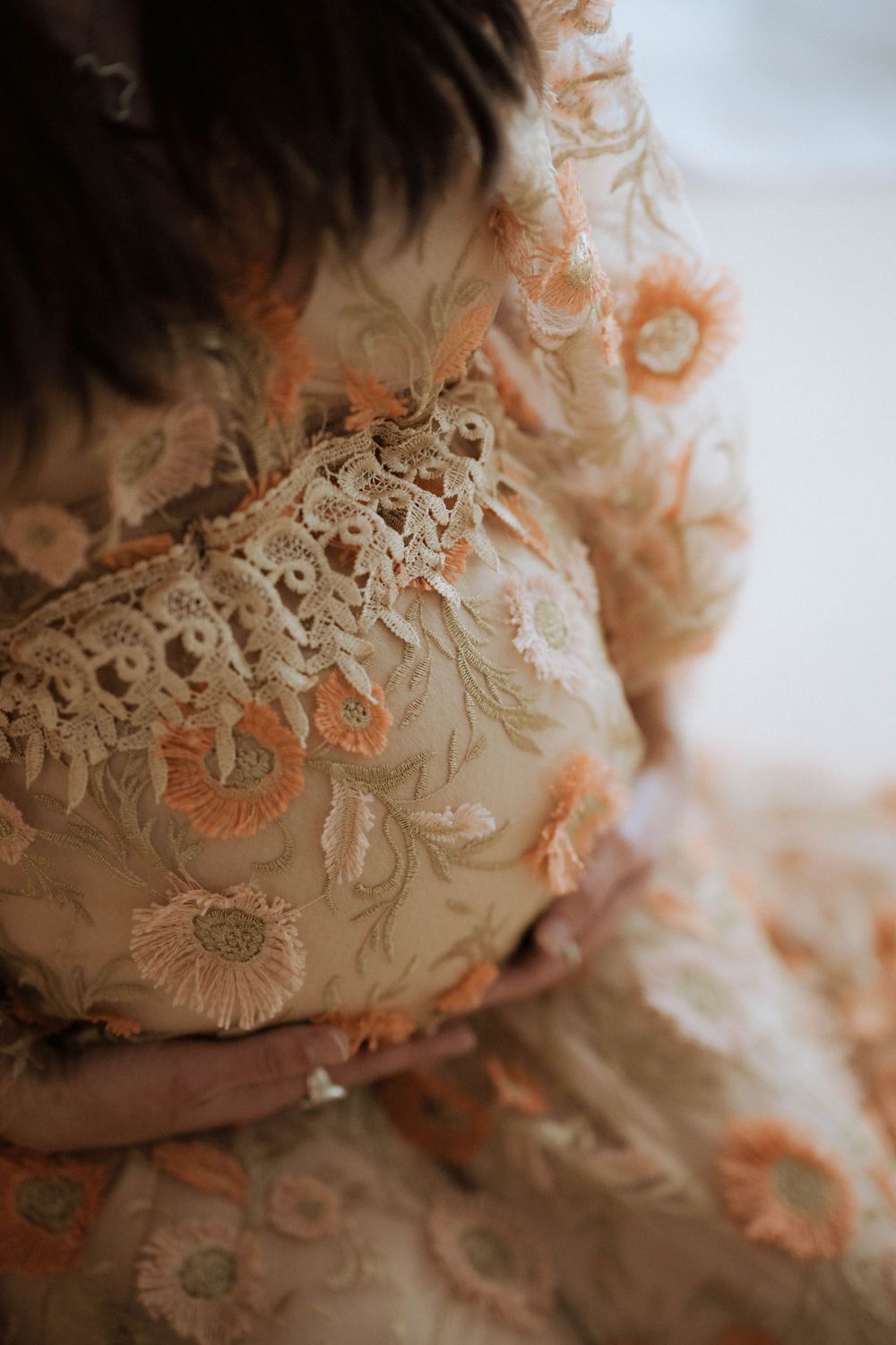 Detail shot of intricate floral lace embroidery on a romantic cream-colored vintage style dress.