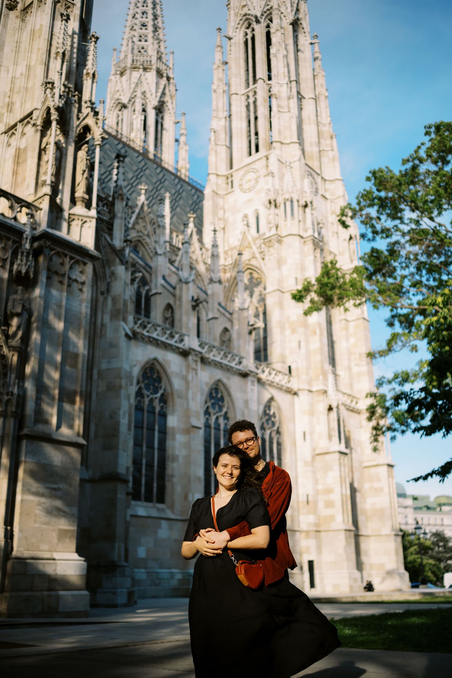 A romantic moment captured outside the towering spires and Gothic architecture of a historic cathedral.