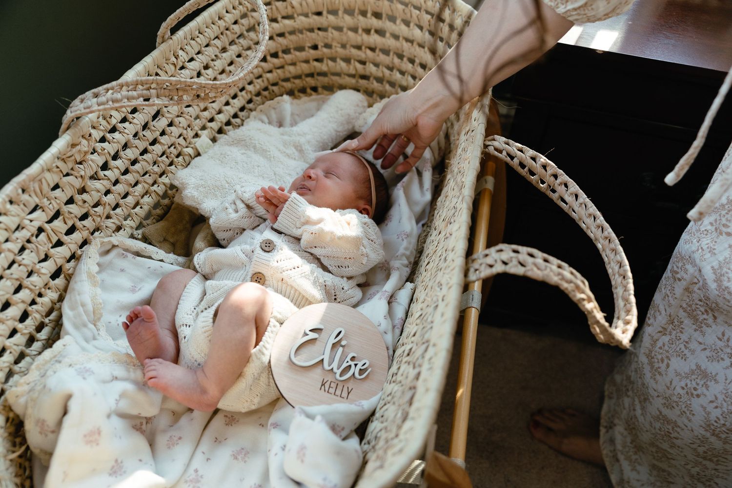 Newborn baby sleeping peacefully in a woven moses basket lined with soft white bedding.