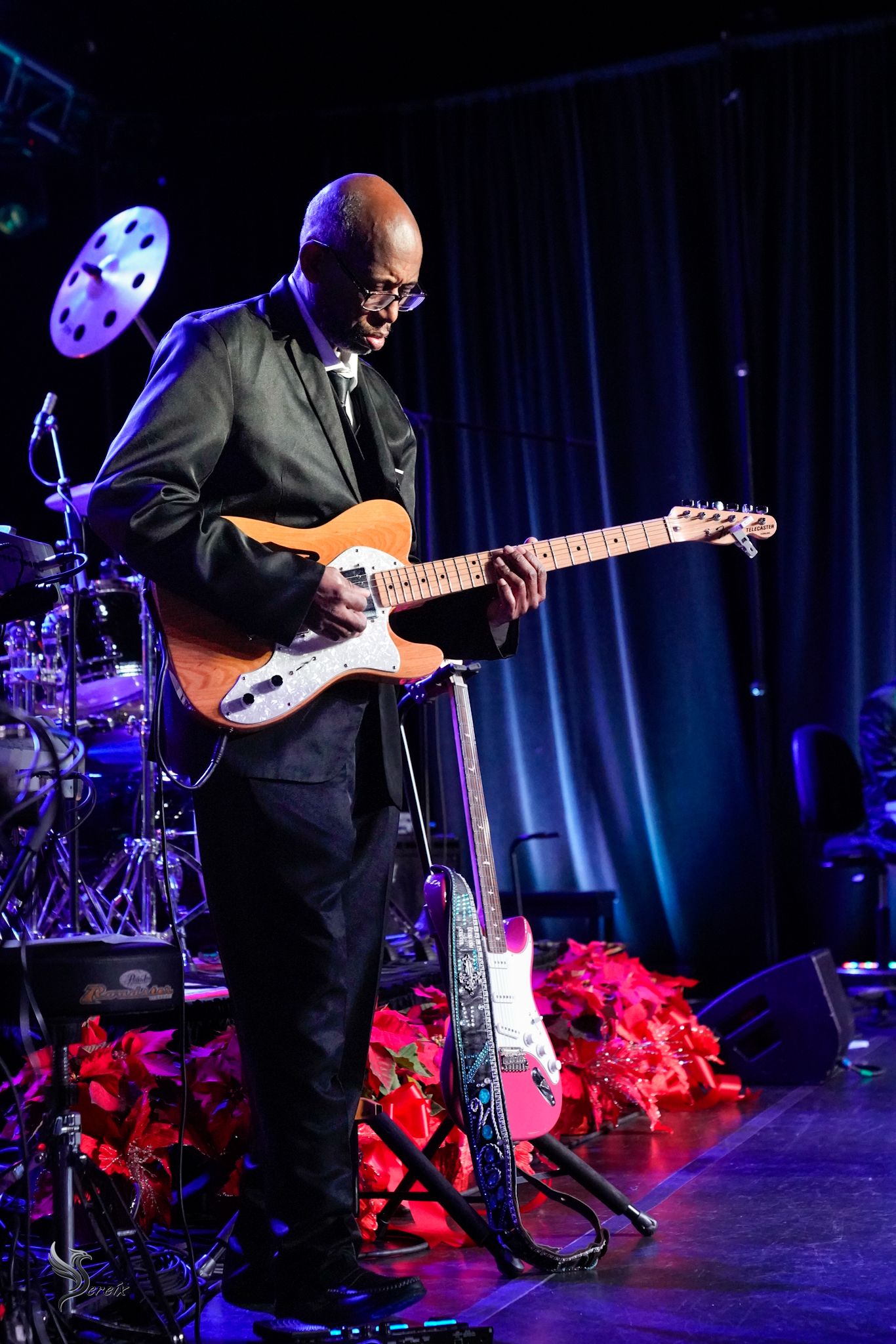 Musician performing live on stage under colorful concert lights, high-energy live music event photography by SRX Media Group