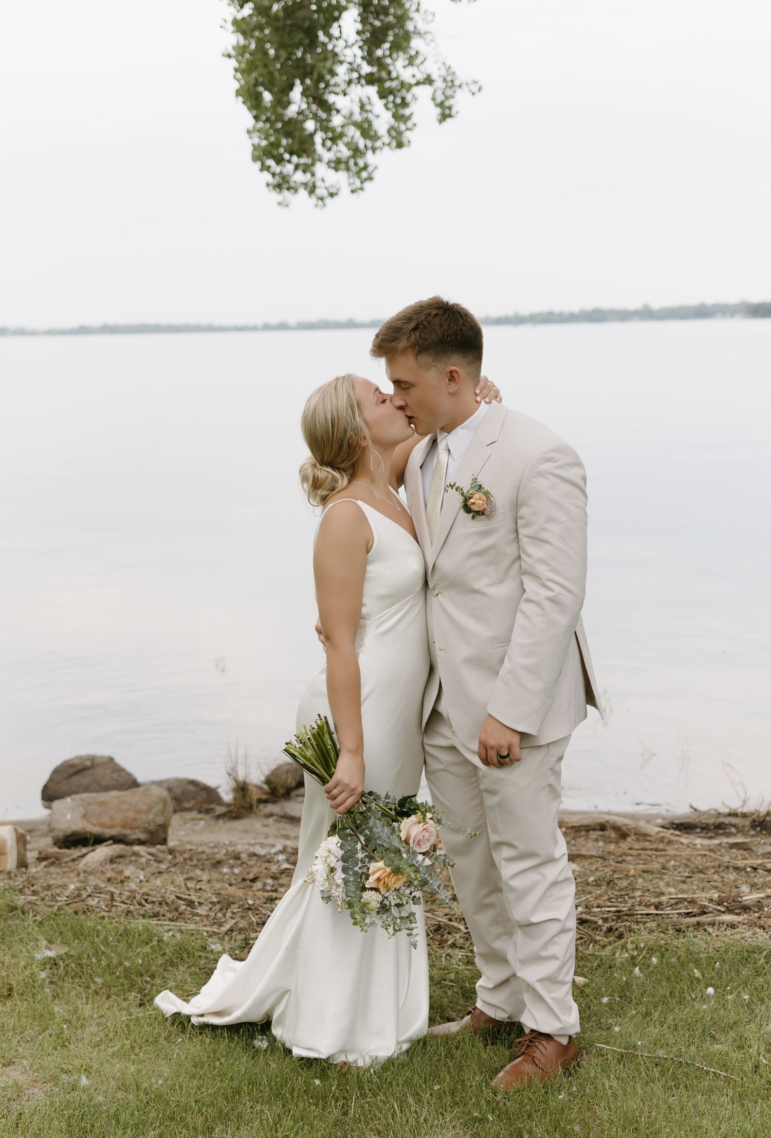 Romantic lakeside wedding portrait with couple in light colored attire.