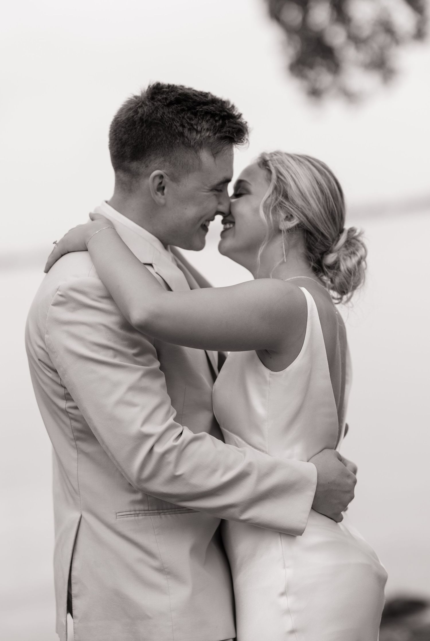 Intimate black and white photo of a couple in wedding attire sharing a tender moment.