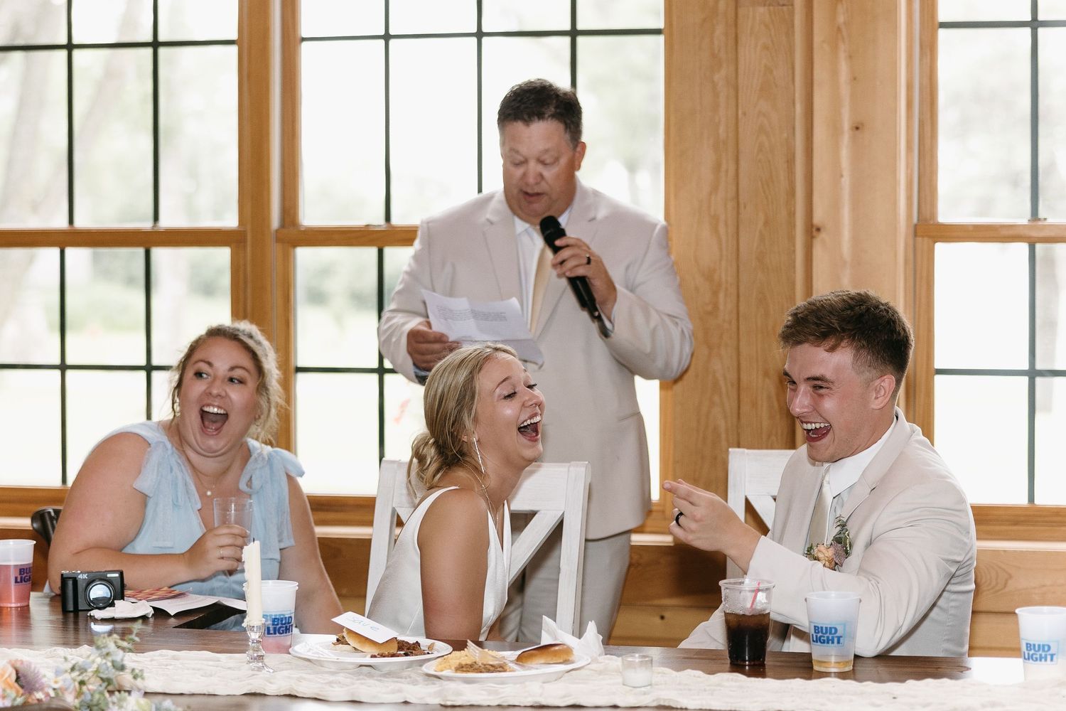 Reception candid moment shows joyful laughter during wedding speeches.