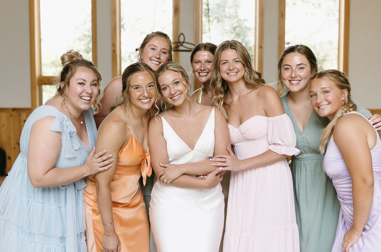 Bridal party in pastel dresses poses together for a group photo.