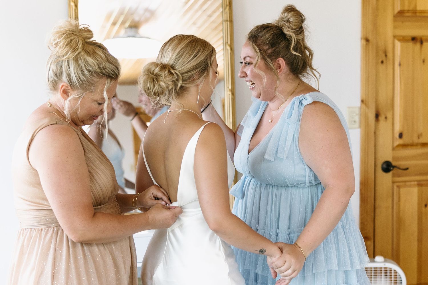 Three women share an emotional moment during wedding preparations.