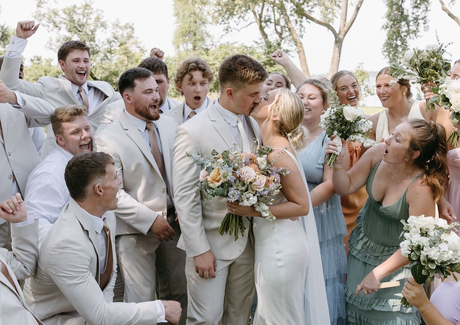 Wedding party celebrates with joy during outdoor photo session.