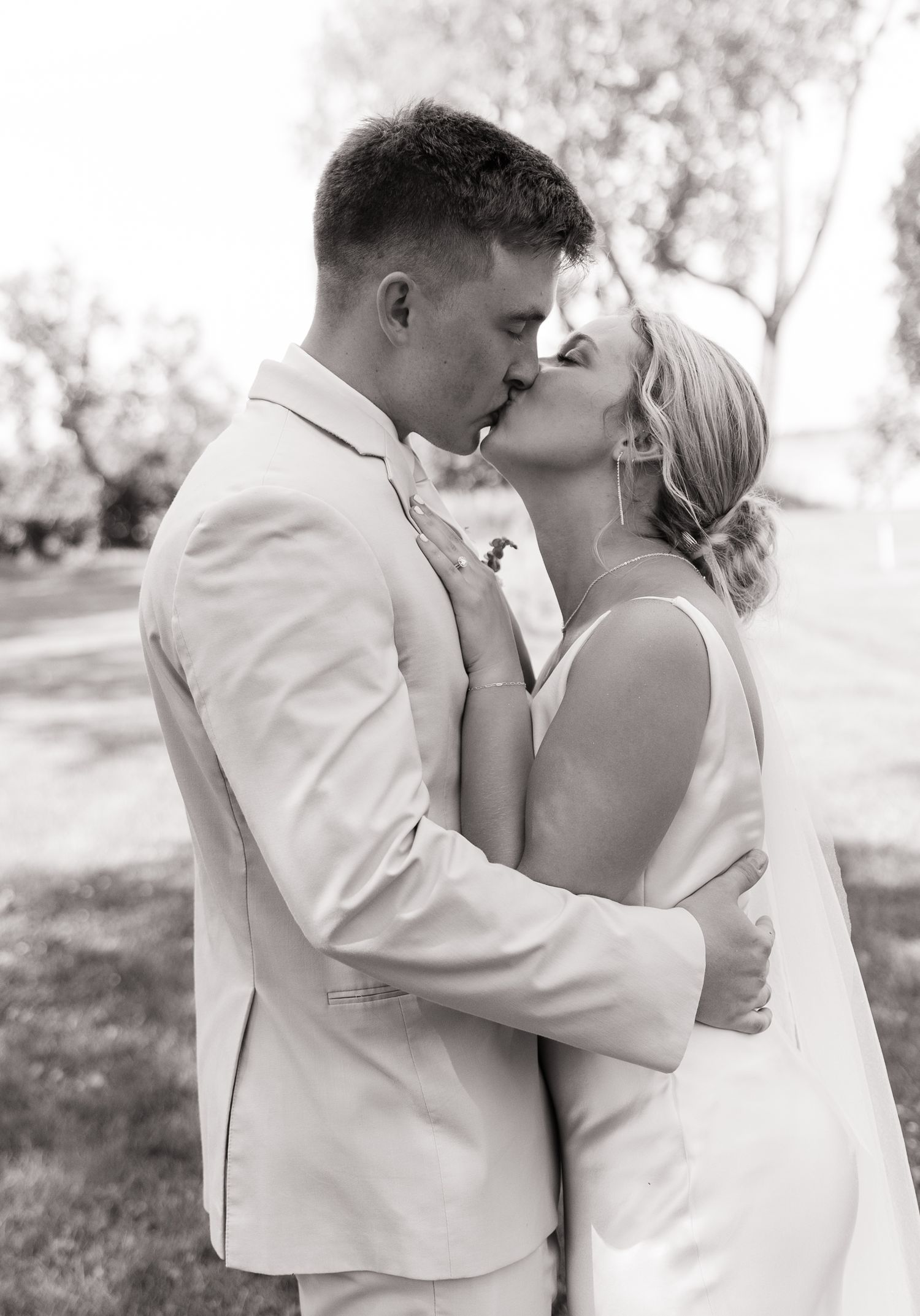 Black and white portrait of newlyweds embracing outdoors.