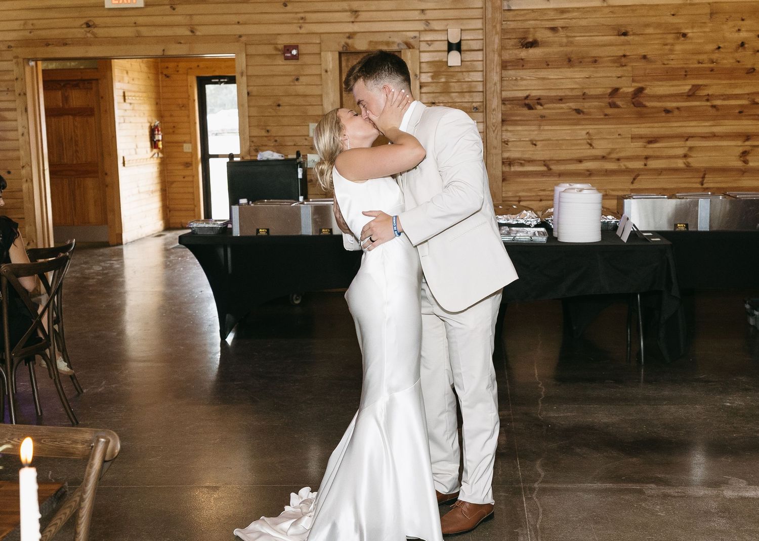 Couple shares first dance in rustic wooden venue reception hall.