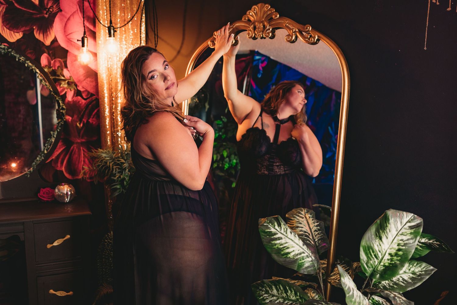 Plus sized woman in black lingerie standing in front of a mirror during confidence boosting boudoir session in a south carolina studio