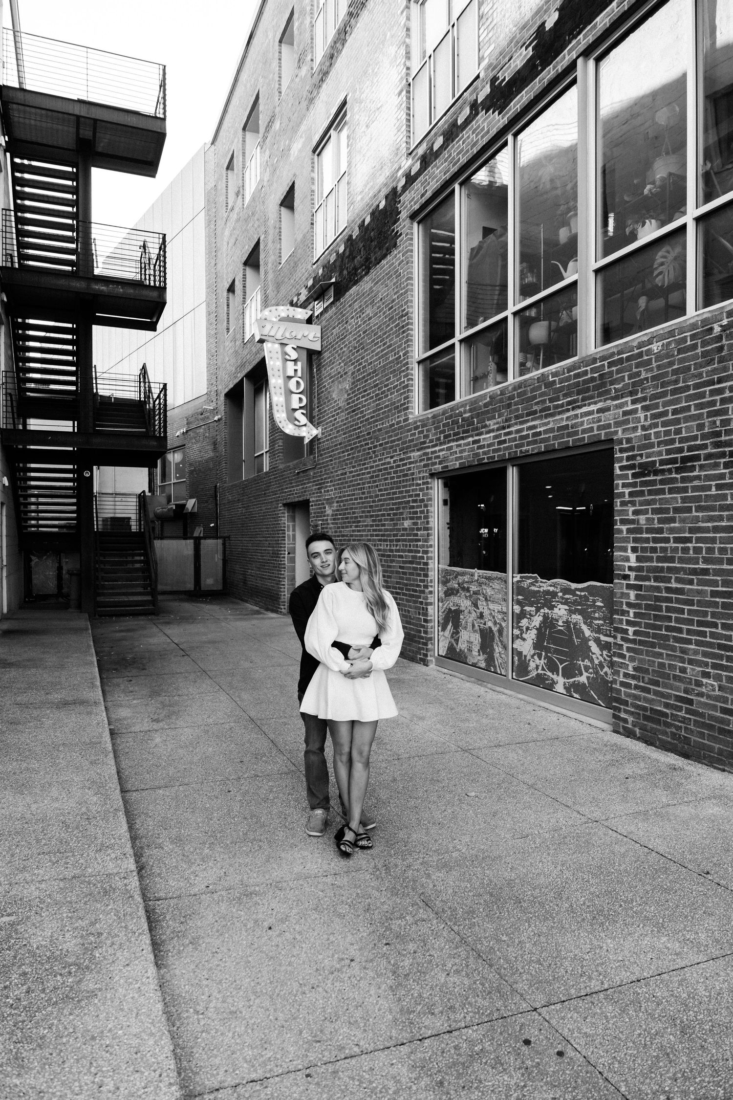 Urban black and white portrait against brick building with fire escape.