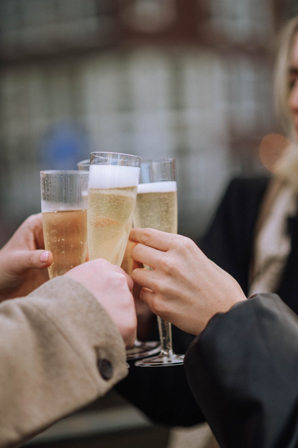 Close-up of hands toasting with champagne glasses during a celebration.