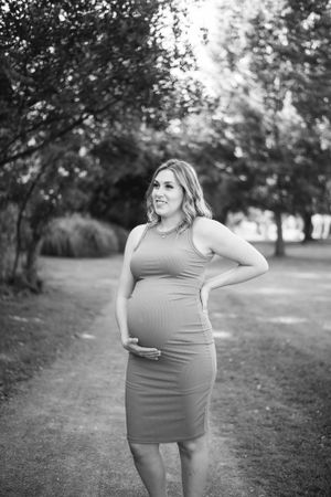 Black and white maternity portrait on nature path with natural lighting.