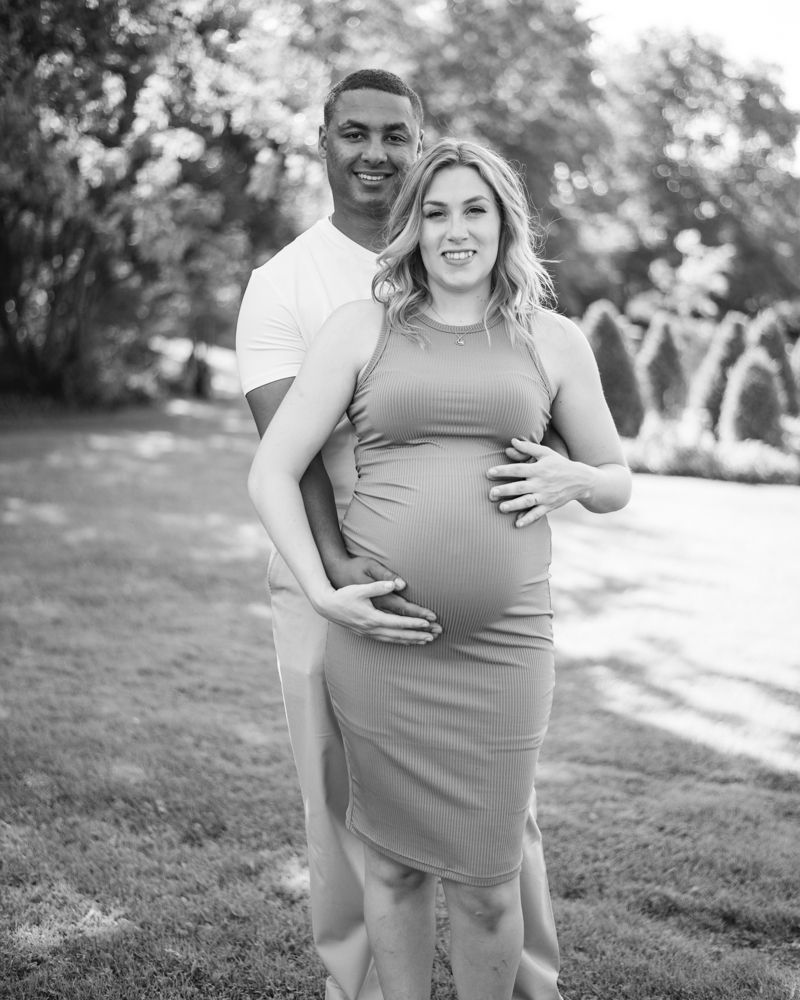 Maternity portrait of couple embracing on garden path in black and white.