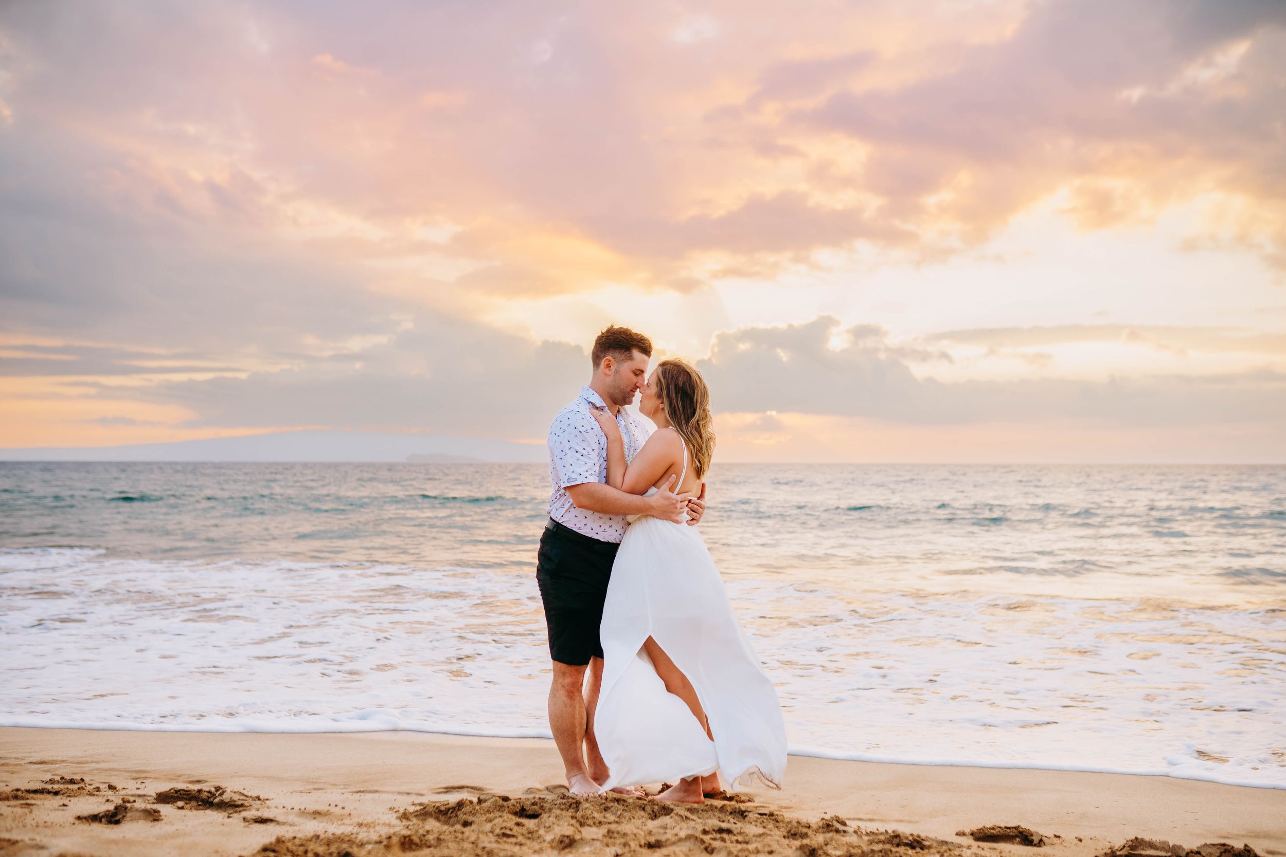 Romantic couple embraces on beach during golden sunset hour in kaanapali maui for couples photography session sunrise family