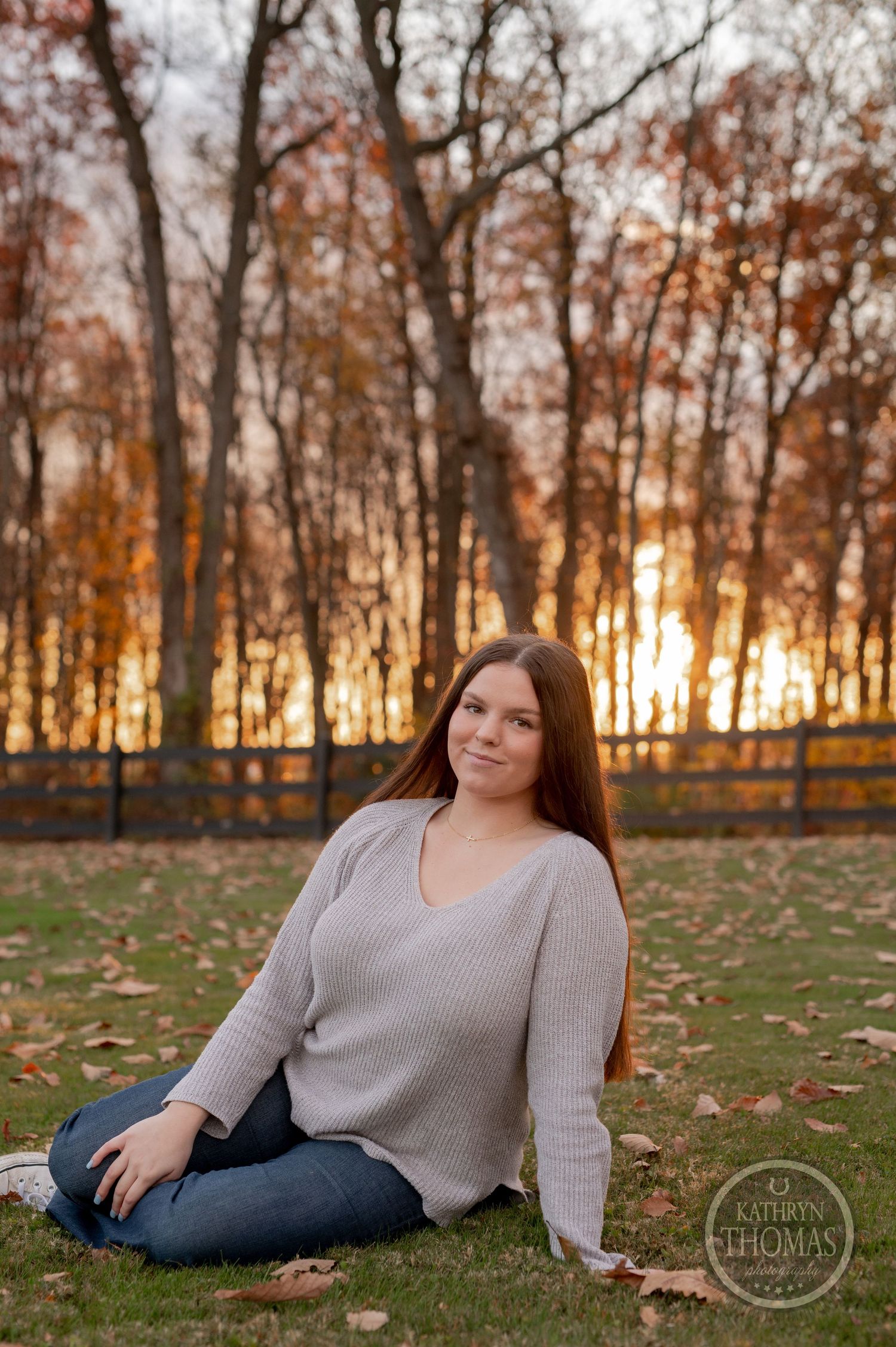 Sunset portrait on grass with glowing autumn trees in background.