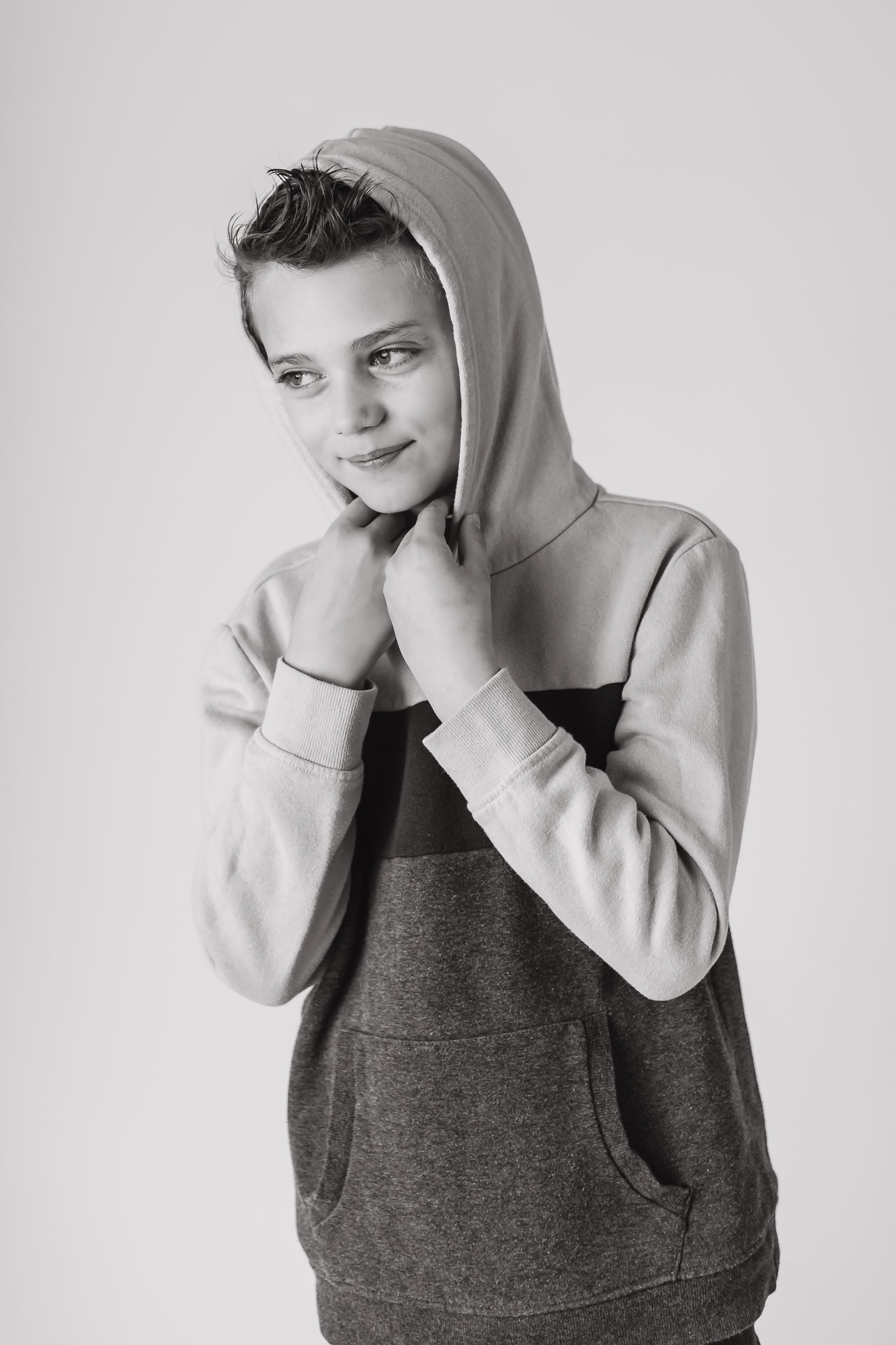 Portrait of person wearing grey hoodie against light background.