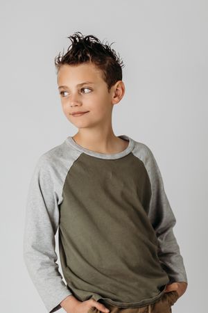 Portrait against grey background wearing olive and grey raglan shirt.