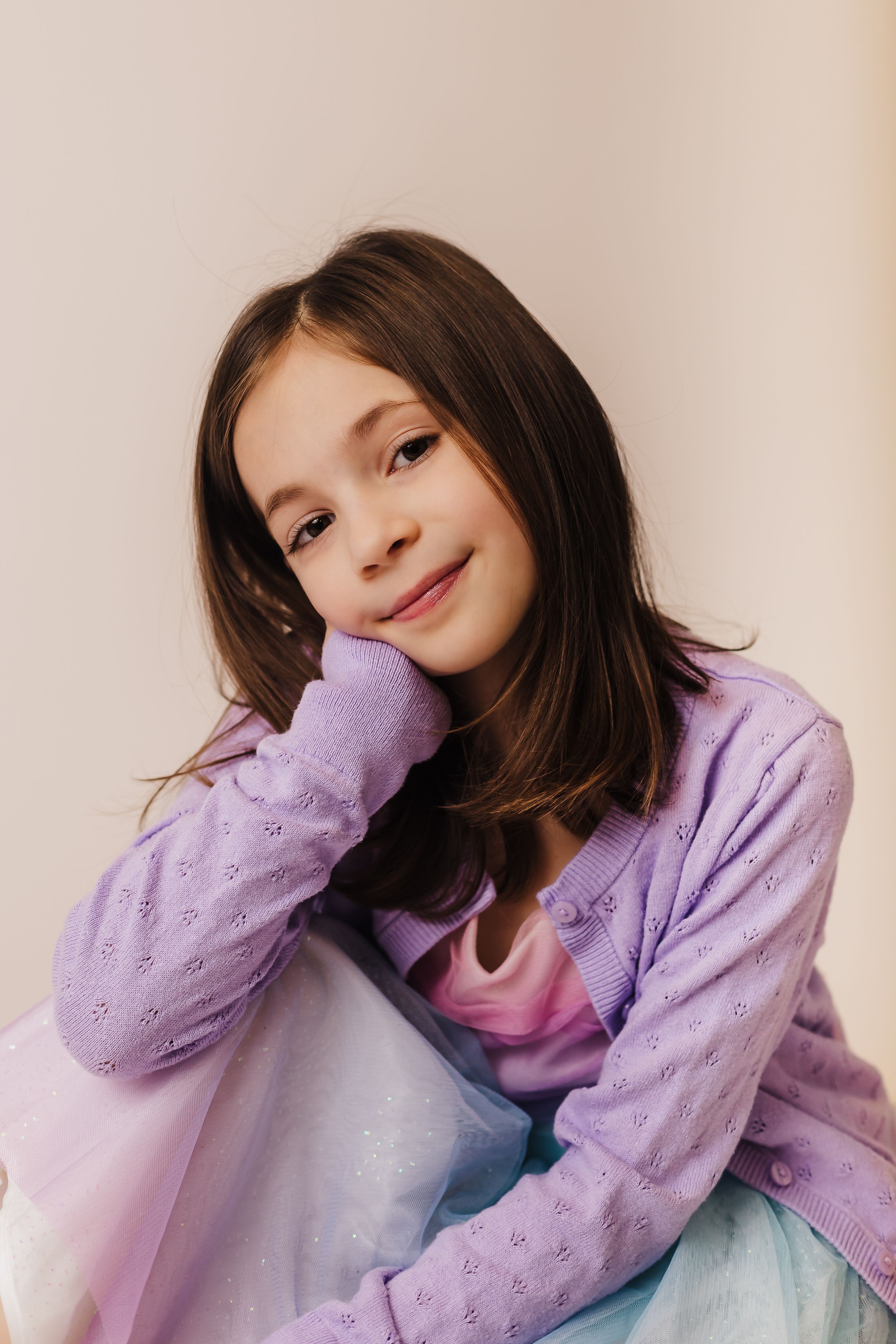 Person in purple sweater poses against light background.