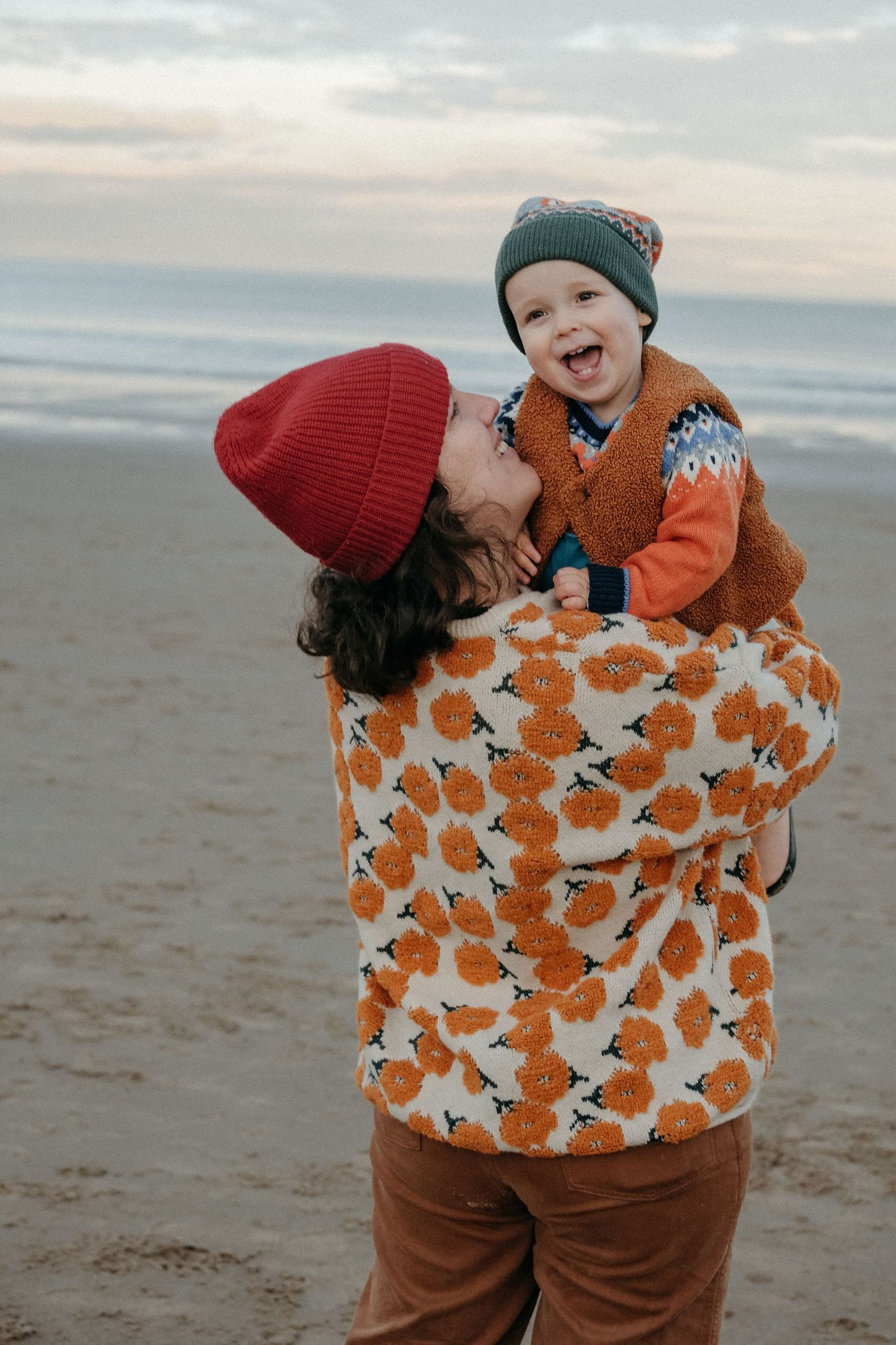 A joyful winter beach scene with parent and child sharing a loving moment in patterned outerwear.