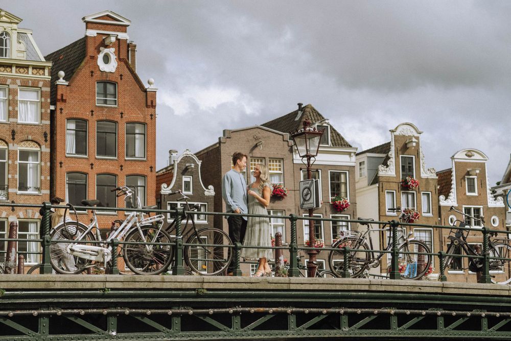Charming Dutch canal houses line a historic street in Amsterdam with traditional architecture and cloudy skies.