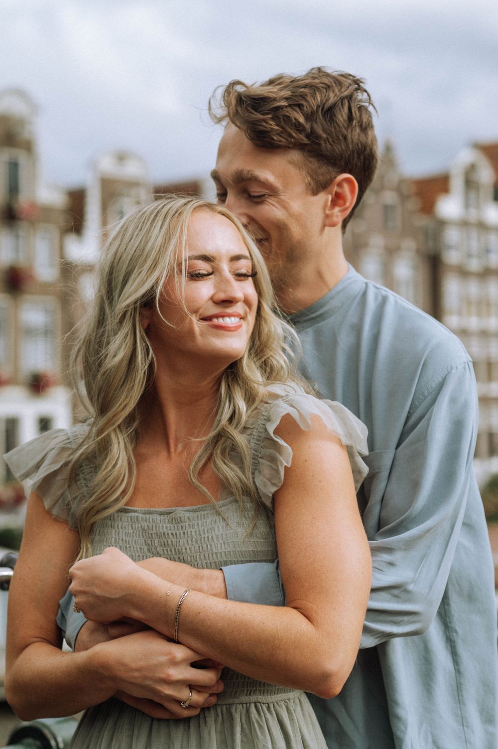 A couple shares an intimate moment while embracing on a cobblestone street in Amsterdam.