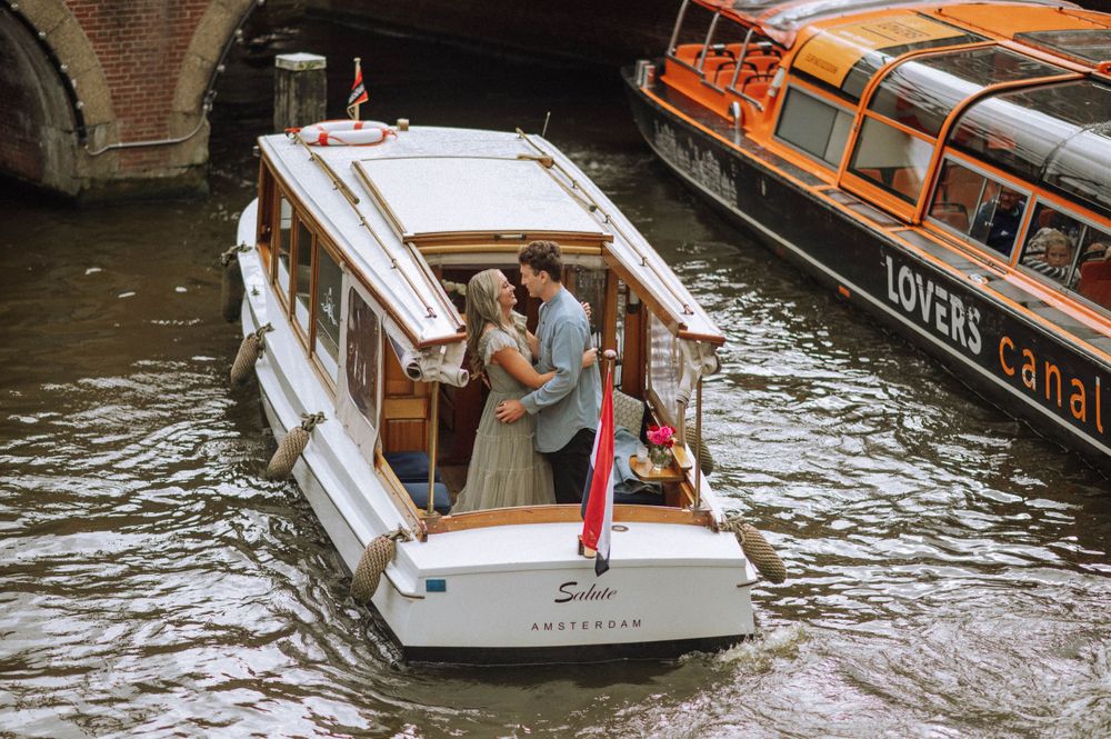 Tourist boat travels through Amsterdam's scenic waterways past historic canal houses.