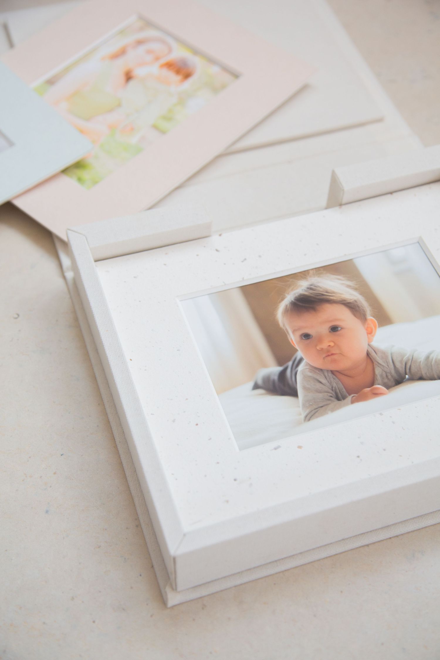 White hardcover book with a small pink rectangle in the center stands upright against a neutral background.